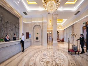 Vienna Hotel Chongqing Chuangyi Park في Shiping: لوبي فيه ناس تقف في كونتر في فندق