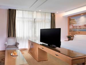 um quarto de hotel com uma televisão numa secretária com uma cama em Vienna Hotel Qingyuan Yingde Guangming Road em Yingde