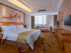 佛山市にあるVienna Hotel Foshan Ceramic Cityの大型ベッドとテレビが備わるホテルルームです。