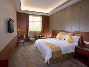 a hotel room with a bed and a desk and a television at Vienna Hotel Dongguan Tangxia Guanlan Lake Golf Club in Dongguan +2 photos
