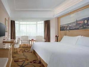 um quarto de hotel com uma grande cama branca e uma janela em Vienna Hotel Huizhou Railway Station em Huizhou