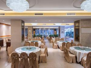 une salle de banquet avec des tables, des chaises et des lustres dans l'établissement Vienna International Hotel Guangzhou Railway Station, à Canton