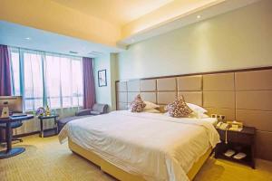 a hotel room with a large bed and a desk at Vienna International Hotel Fuzhou Cangshan Longfu in Fuzhou
