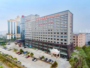 un grand bâtiment avec des voitures garées dans un parking dans l'établissement Vienna Hotel Shenzhen Longgang Ainan Road, à Longgang