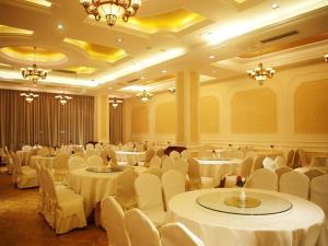 a banquet hall with white tables and chairs and chandeliers at Vienna Hotel Zhangjiajie North Railway Station in Zhangjiajie