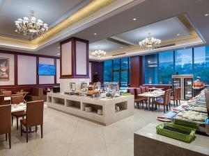 um restaurante com mesas, cadeiras e lustres em Vienna International Hotel (Zhuzhou liyu store) em Zhuzhou