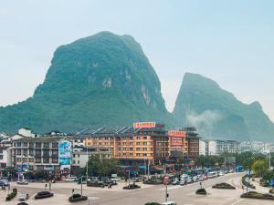 a city with a mountain in the background with cars at Vienna International Hotel Yangshuo West Street in Yangshuo