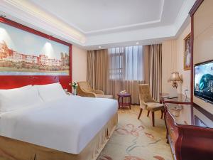 Vienna Hotel Jiangsu Shuyang Middle Renmin Road في Shuyang: غرفة الفندق بسرير كبير ومكتب