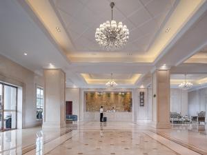 a person standing in a large lobby with a chandelier at Vienna Hotel Guangzhou South Panyu Bridge in Guangzhou
