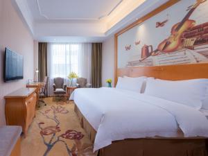 広州市にあるVienna International Hotel Guangzhou Changlong Qifu Xincunの大きなベッドとデスクが備わるホテルルームです。