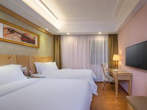 a hotel room with two beds and a desk and a television at Vienna 3 Best Hotel Exhibition Center Chigang Road in Guangzhou
