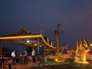 een groep mensen die 's nachts aan tafel zitten in een paviljoen bij Vienna Hotels(JingHong BinJiang JunJuan) in Jinghong