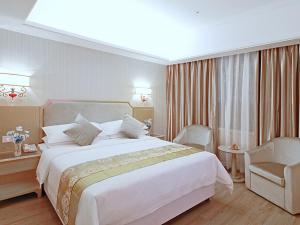 ein Hotelzimmer mit einem großen Bett und einem Stuhl in der Unterkunft Vienna 3 Best Hotel Baise Zhongshan Road City Central in Baise