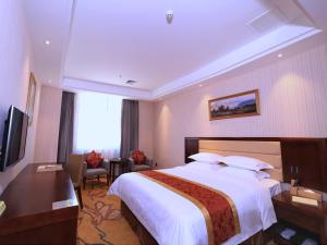 a hotel room with a large bed and a television at Vienna Hotel Shenzhen Gongming Bus Station in Kung-ming