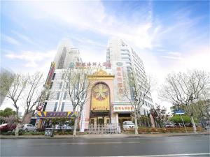 un edificio con una torre de reloj delante de él en Vienna Hotel Shanghai Yangpu Wujiaochang en Shanghái