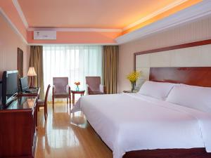 a hotel room with a large bed and a television at Vienna Hotel Shenzhen Aiguo Road in Shenzhen