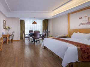 een hotelkamer met een groot bed en een tafel en stoelen bij Vienna Hotel Dongguan Chengcaiyuan International Plaza in Dongguan