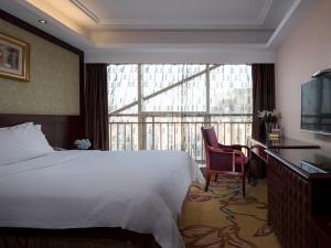 a bedroom with a bed and a desk and a large window at Vienna International Hotel Changzhou Hutang in Changzhou