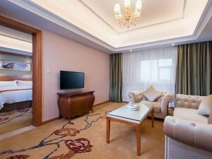 a living room with a couch and a tv and a bed at Vienna Hotel Chaoyang High-Speed Train Station in Shantou