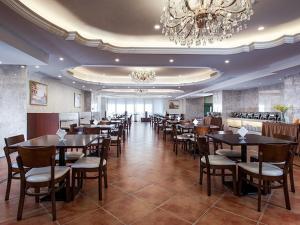 a dining room with tables and chairs and a chandelier at Vienna International Hotel Guangdong Zhongshanbei Station in Zhongshan