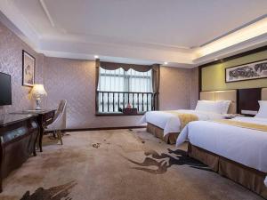 a hotel room with two beds and a desk and a window at Vienna 3 Best Hotel Meizhou Mei County People Square in Meizhou