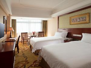 a hotel room with two beds and a table at Vienna Hotel Shenzhen Futian Bagua Road in Shenzhen