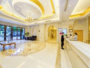 a man and woman standing at a counter in a lobby at Vienna International Hotel Zhuzhou Railway Station Central Plaza in Zhuzhou