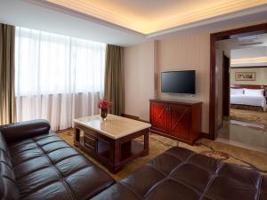 a living room with a couch and a flat screen tv at Vienna Hotel Shenzhen Futian Bagua Road in Shenzhen