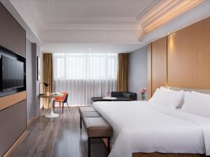 ein Hotelzimmer mit einem großen Bett und einem TV in der Unterkunft Vienna International Hotel Zhongshan Shiqi Kanghua Road in Zhongshan