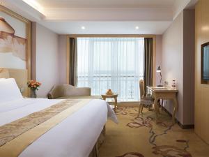 a hotel room with a bed and a desk and a window at Vienna Hotel Guangxi Nanjing Nanhu Park in Nanning +2 photos