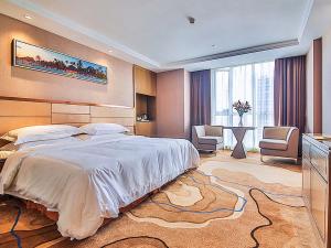 a bedroom with a large bed and a room with a table at Vienna International Hotel Huhan Jiedaokou in Wuhan