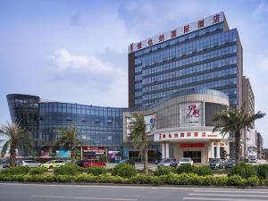 a large building with cars parked in front of it at Vienna International Hotel Guangdong Foshan Nanhai Heshun in Nanhai