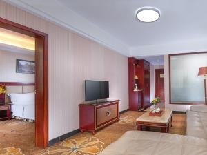 a living room with a couch and a flat screen tv at Vienna Hotel Longgang Nanlian in Longgang