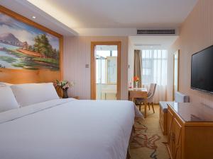 a hotel room with a large bed and a flat screen tv at Vienna Hotel(Changshu Sitir Store) in Zhangshu