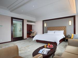佛山市にあるVienna hotel (sanshui wanda store)のベッドとテーブルが備わる広いホテルルームです。