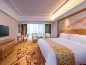 a hotel room with a large bed and a television at Vienna Hotel Guangdong Zhongshan Tanzhou in Zhongshan