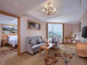 a living room with a couch and a bed at Vienna International Hotel Guangzhou Xintang Jean Fangzhicheng in Zengcheng