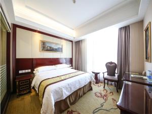 Vienna Hotel Shanghai Hongqiao Convention & Exhibition Center في شانغهاي: غرفة فندقية بسرير كبير وكرسي