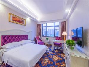 ein Hotelzimmer mit einem Bett, einem Schreibtisch und einem TV in der Unterkunft Vienna Hotel Guilin ShiFu Branch in Lingui