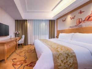 a hotel room with a large bed and a desk at Vienna Hotel Guangdong Zhongshan Tanzhou in Zhongshan