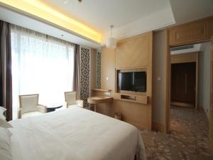 a hotel room with a bed and a flat screen tv at Vienna Hotel Waigaoqiao in Shanghai