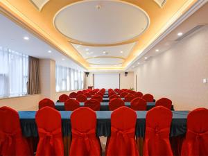 a conference room with a long table and red chairs at Vienna Hotel Nanjing Olympic Sports Center in Nanjing