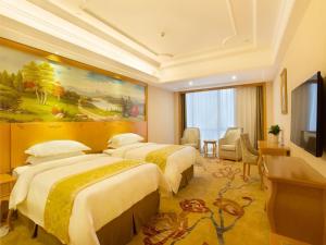 una camera d'albergo con tre letti e una televisione di Vienna International Hotel Changsha Hongxing a Changsha