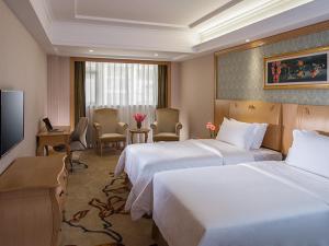 a hotel room with two beds and a television at Vienna Hotel Shenzhen Nanshan Yilida in Shenzhen