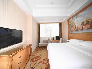 um quarto de hotel com uma cama e uma televisão de ecrã plano em Vienna Hotel Shenzhen Nanxin Road em Shenzhen