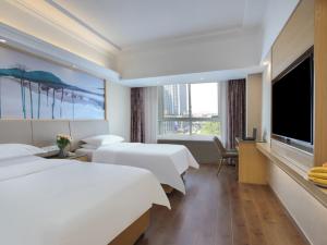 a hotel room with two beds and a flat screen tv at Vienna International Hotel Jingdezheng People Square in Jingdezhen