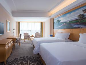 um quarto de hotel com duas camas, uma secretária e uma mesa em Vienna Hotel Dongguan Tangxia Garden Street em Tangxia