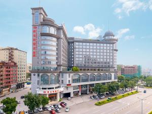 a large building in a city with cars on a street at Vienna Hotel Dongguan Hou Avenue Jinzuo in Hetian