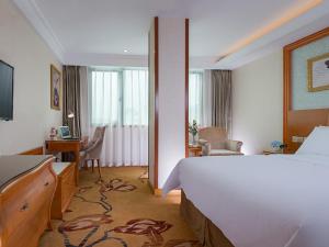 泉州市にあるVienna Hotel (Quanzhou West Lake Store)のベッドとデスクが備わるホテルルームです。