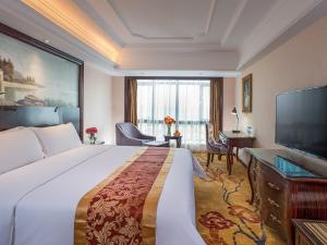 a hotel room with a large bed and a flat screen tv at Vienna International Hotel Huizhou Huidong Honghaiwan in Huidong